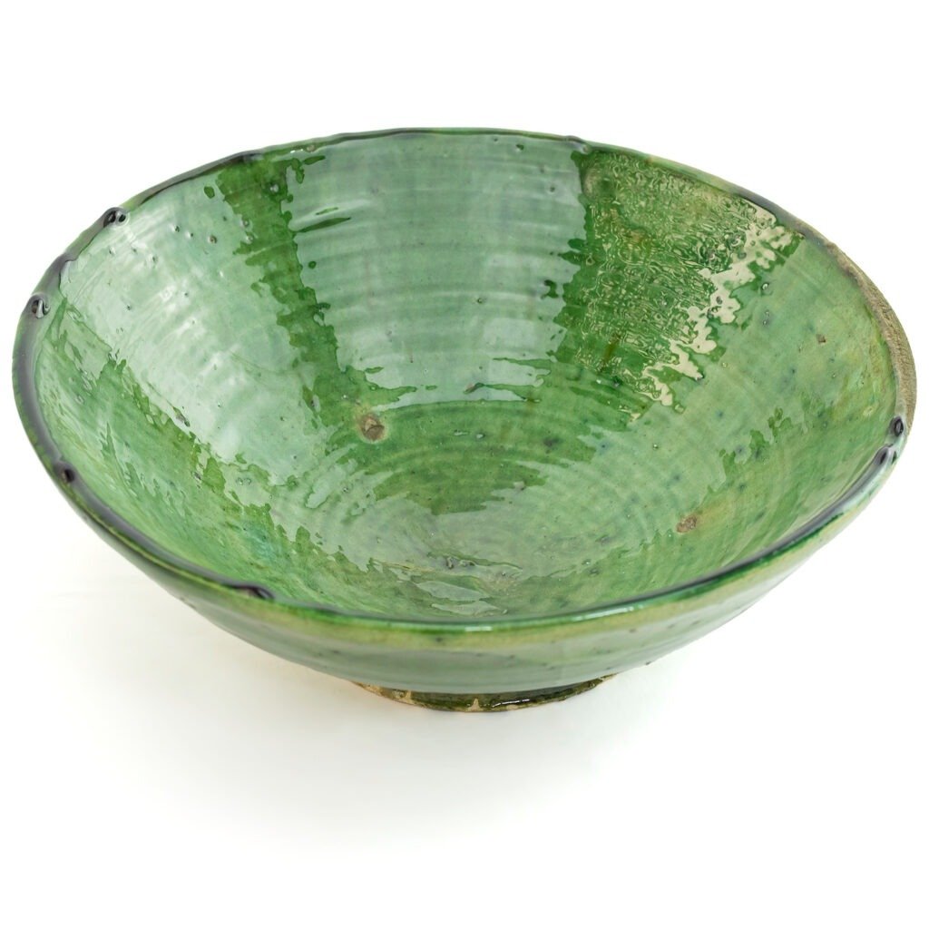 A green, glazed ceramic bowl with a slightly irregular rim and a subtle spiral pattern on the inside, reminiscent of traditional Tamegroute pottery.