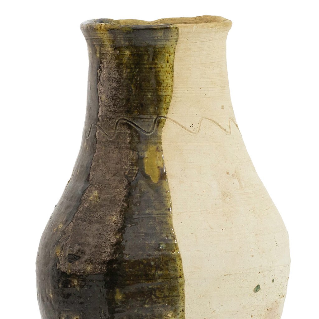 A ceramic vase inspired by Tamegroute pottery features a split design with glazed dark brown and plain beige sides, separated by an uneven wavy line.