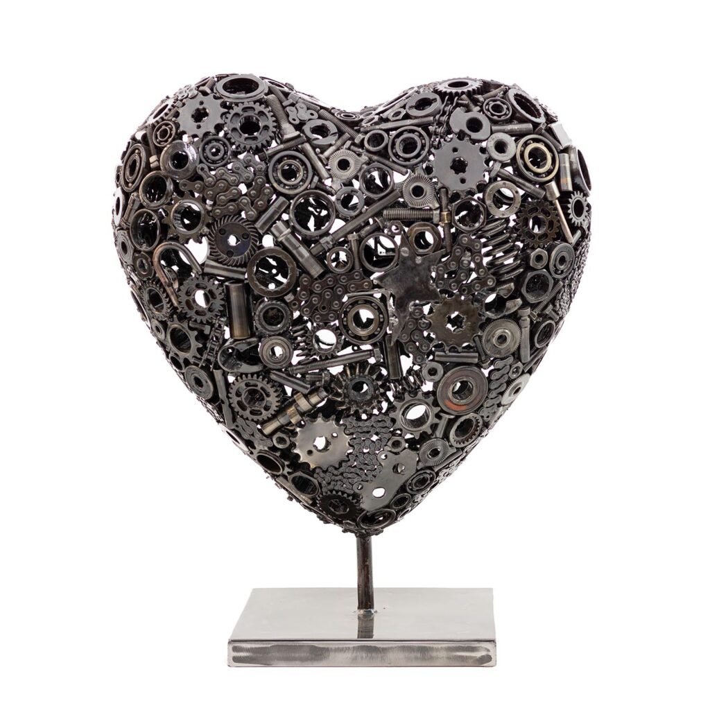 The Heart of Steel sculpture features a heart-shaped design crafted from metal gears and intricate mechanical parts, all mounted on a sleek rectangular base.