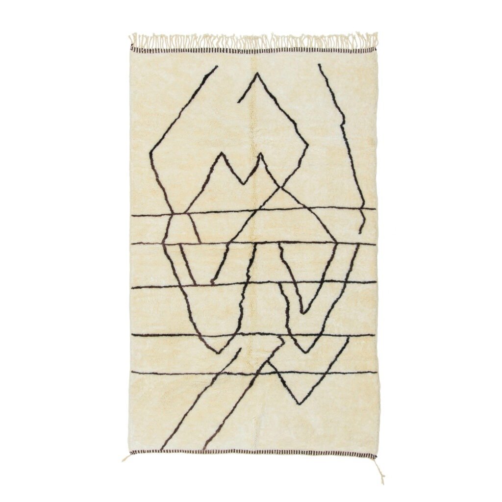 A beige rug features abstract black line patterns and fringe on the top and bottom edges, adding a touch of contemporary elegance to any room.