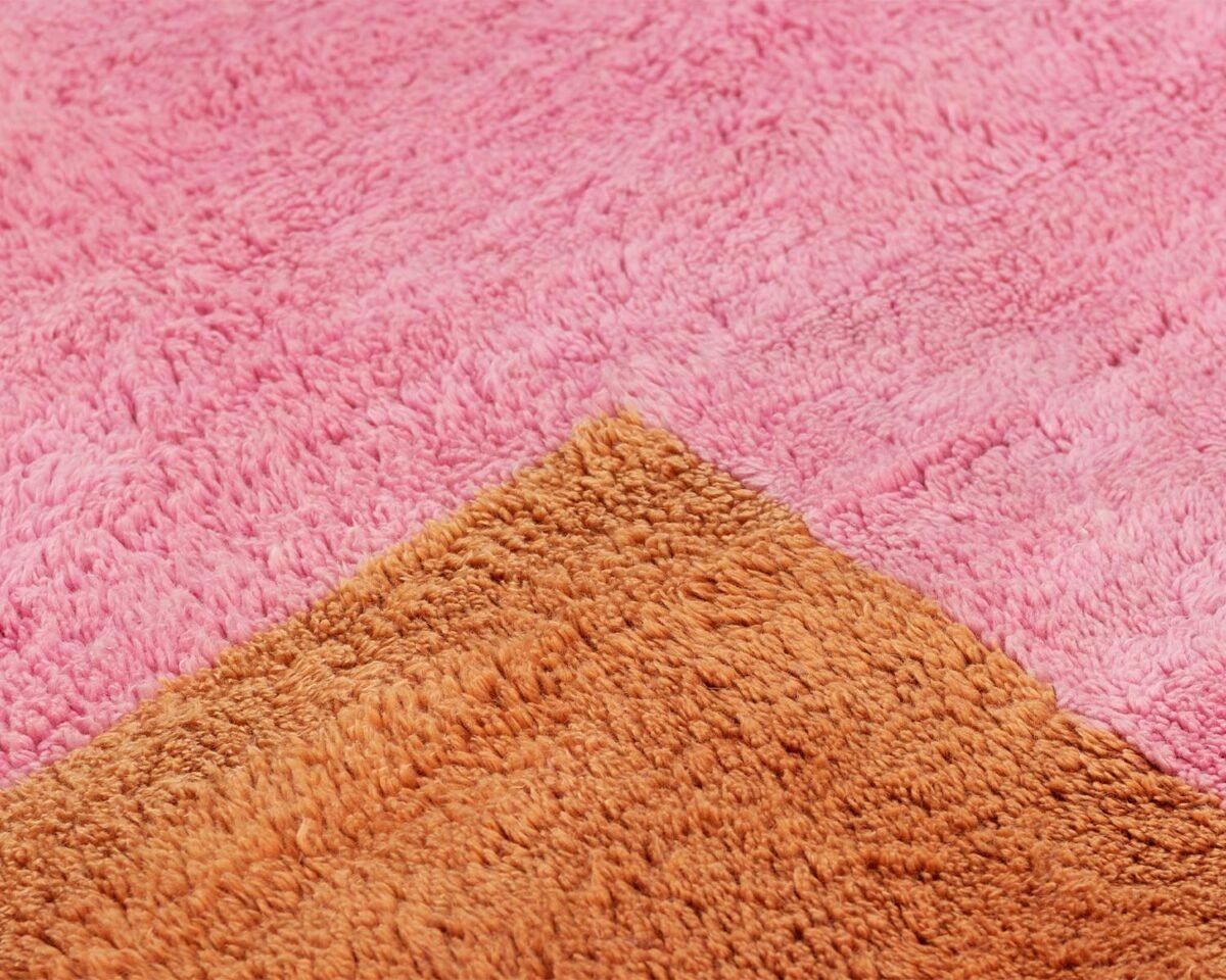 A close-up view highlights the rich texture of a pink and brown fuzzy fabric, seamlessly divided by a diagonal line.
