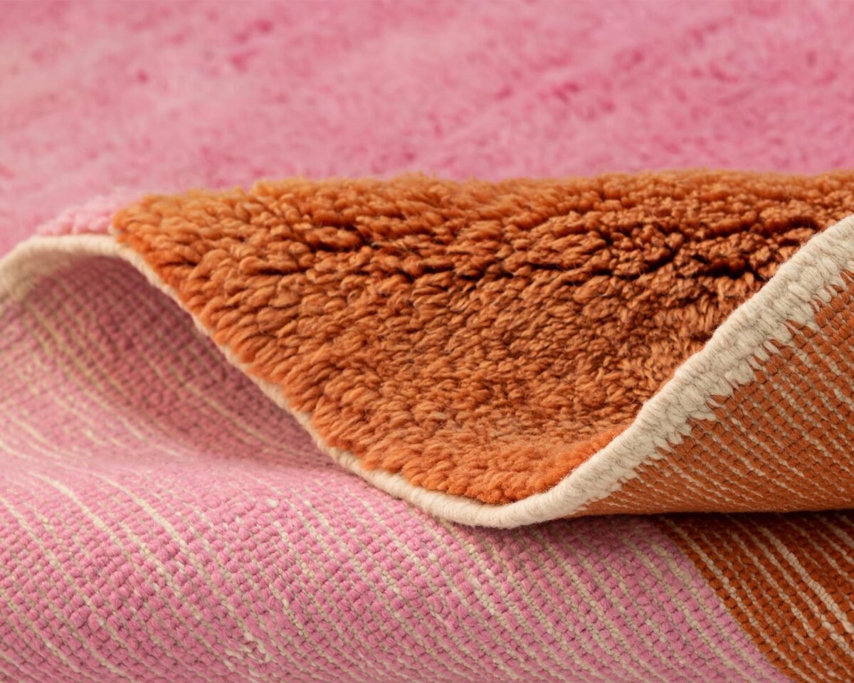 A close-up reveals the intricate details of a textured fabric, featuring a pink woven pattern atop a plush brown fleece underside. This exquisite design offers both elegance and comfort, showcasing the harmonious blend of color and texture.