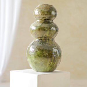 A green, glossy, triple-gourd-shaped ceramic vase elegantly stands on a white pedestal, set against a neutral background.
