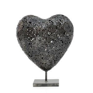 Handmade metal heart sculpture with intricate patterns, gracefully mounted on a square base, perfect for adding a touch of elegance to your home decor.