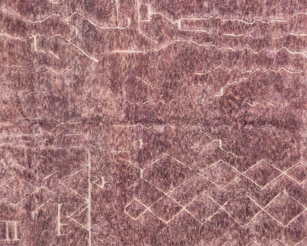 Close-up of a textured pink surface with geometric and wavy patterns, resembling a blend of lines and curves, reminiscent of a hand knotted rug.