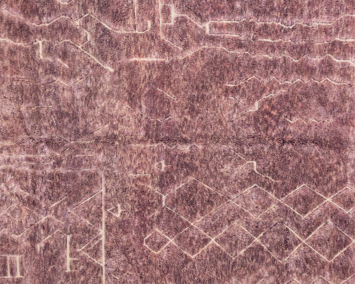 Close-up of a textured pink surface with geometric and wavy patterns, resembling a blend of lines and curves, reminiscent of a hand knotted rug.