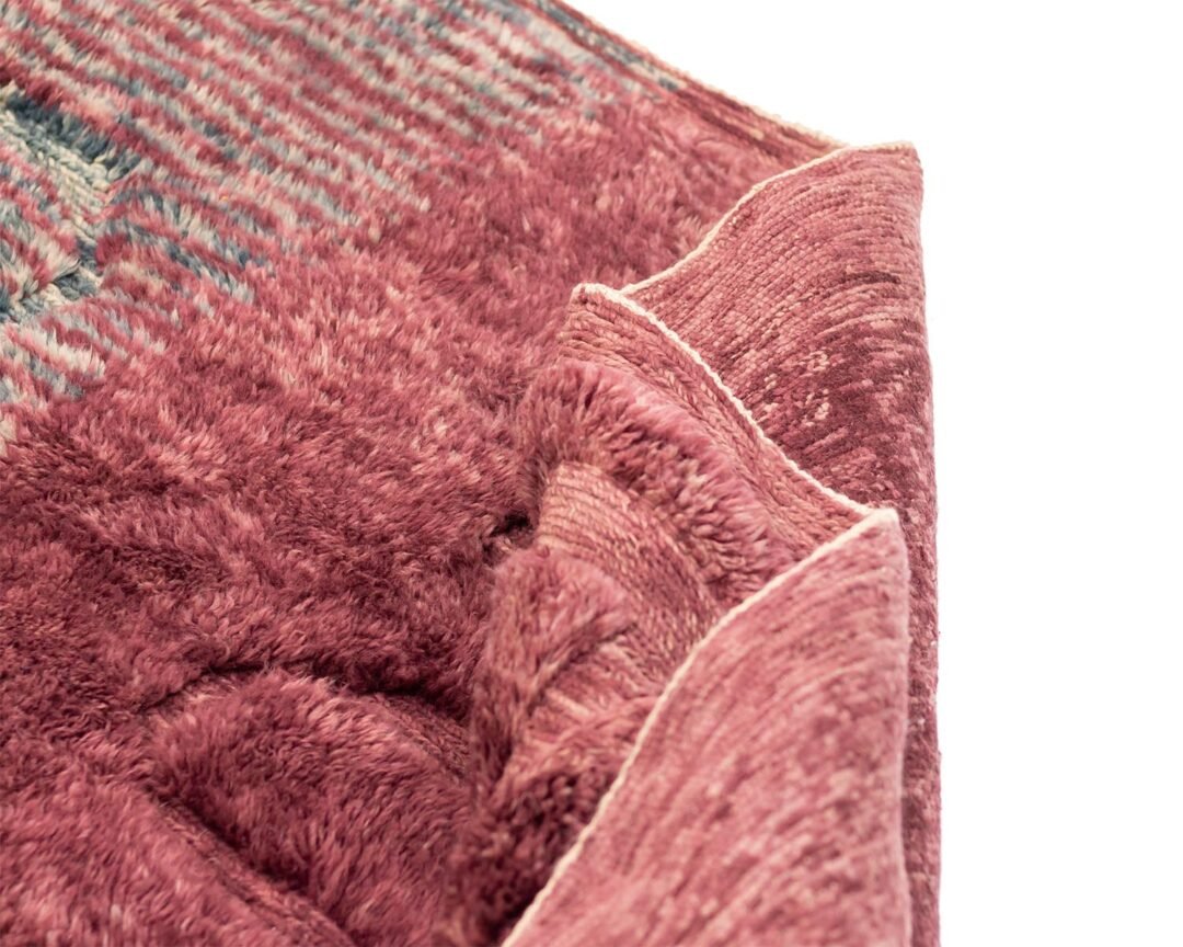 Close-up of a hand-knotted Moroccan rug with a plush, textured pink and red surface.