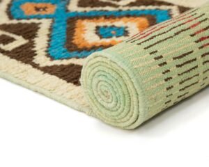 A rolled-up rug with a geometric pattern in brown, blue, orange, and cream hues, accented by a light green edge, elegantly displayed on a white background.