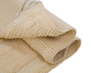 A close-up of a folded beige textured fabric with visible loops and fringe edges.