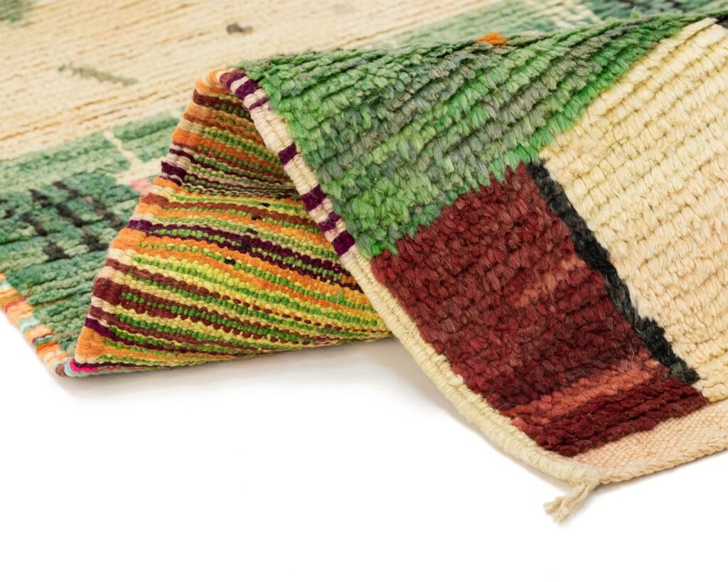 A multicolored woven rug with vibrant patterns is partially folded, revealing intricate striped designs underneath.