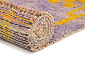A vibrant multicolored rug showcasing yellow, purple, and black geometric patterns set against a white background. This stylish piece adds a pop of color to any room.