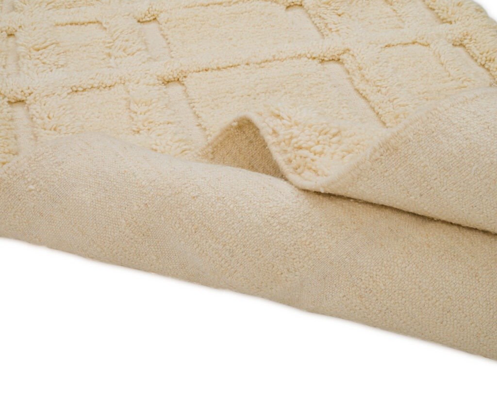 Close-up of a beige textured runner rug with a geometric pattern. Edges are slightly folded, revealing a plush and soft surface.