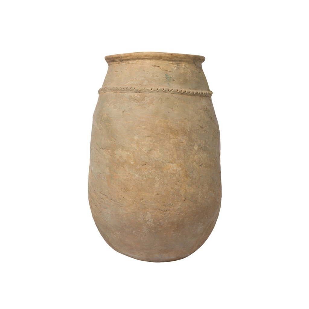 A large, beige, ancient clay pot resembles vintage Berber jars with its rounded base and simple lined design around the top.