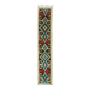 A long, narrow woven rug with tribal geometric patterns in blue, red, brown, and beige features diamond and rectangular shapes along with small fringe details at the top.