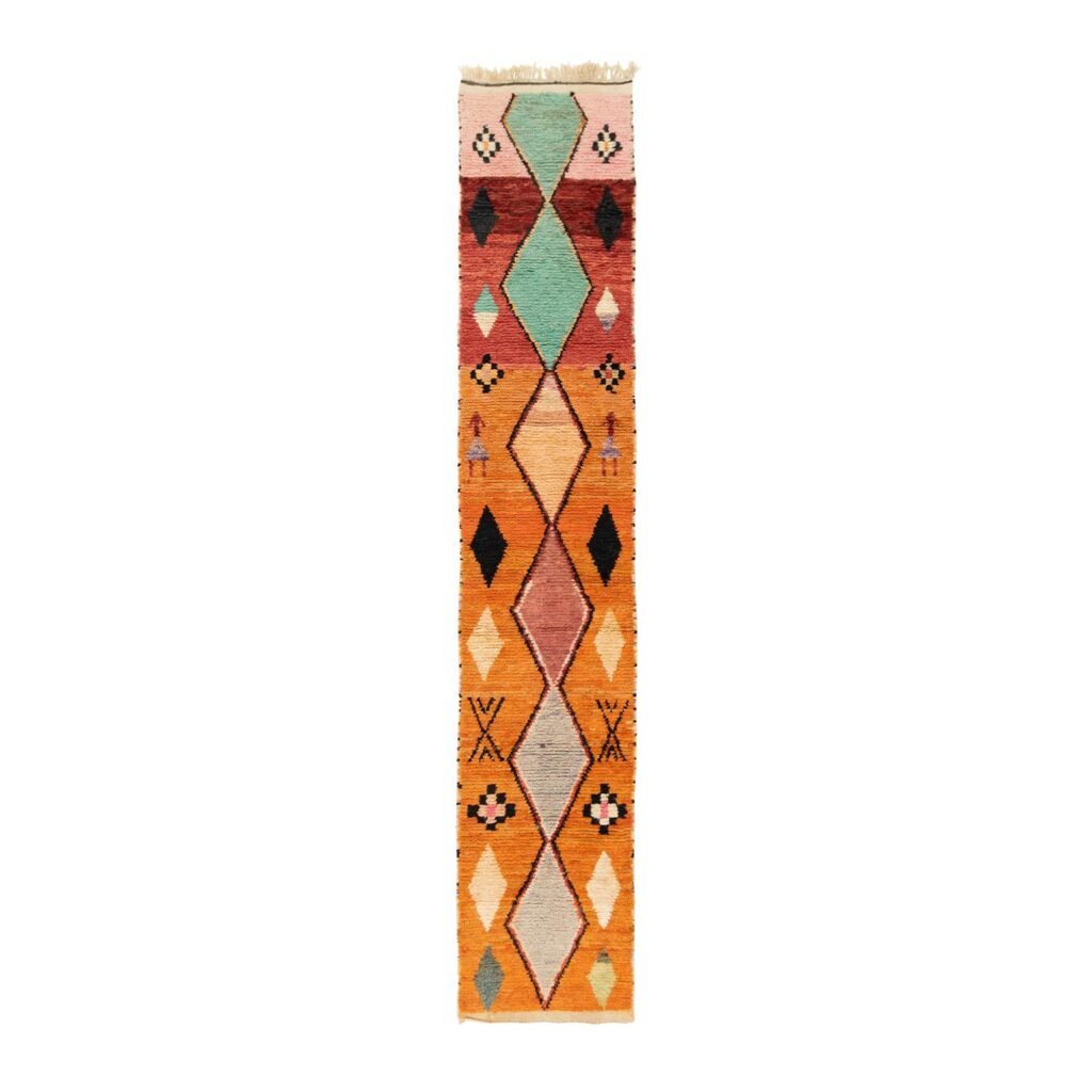A vibrant runner rug showcasing a colorful geometric pattern with an array of shapes and shades like orange, green, and pink set in symmetrical harmony on a pristine white background.