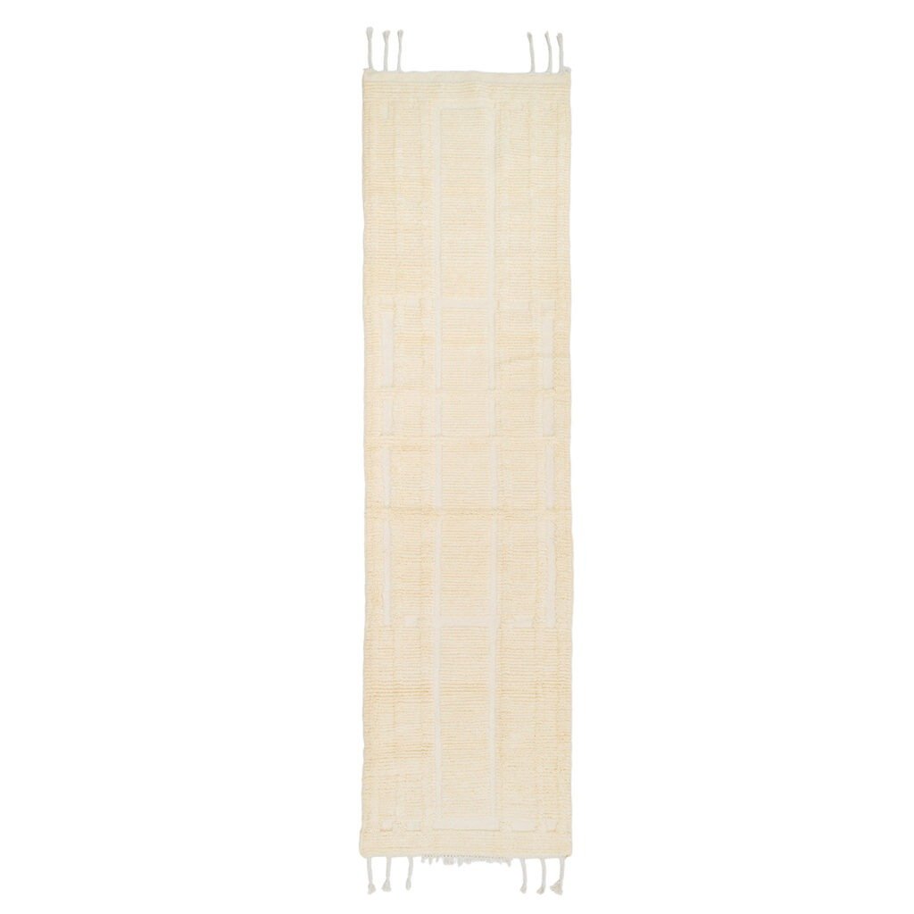 A long, narrow hand-knotted beige runner rug with a textured pattern. Fringes are visible at both ends.