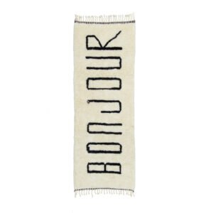 A white rectangular runner rug featuring the word BONJOUR in bold black letters. The edges are elegantly fringed.