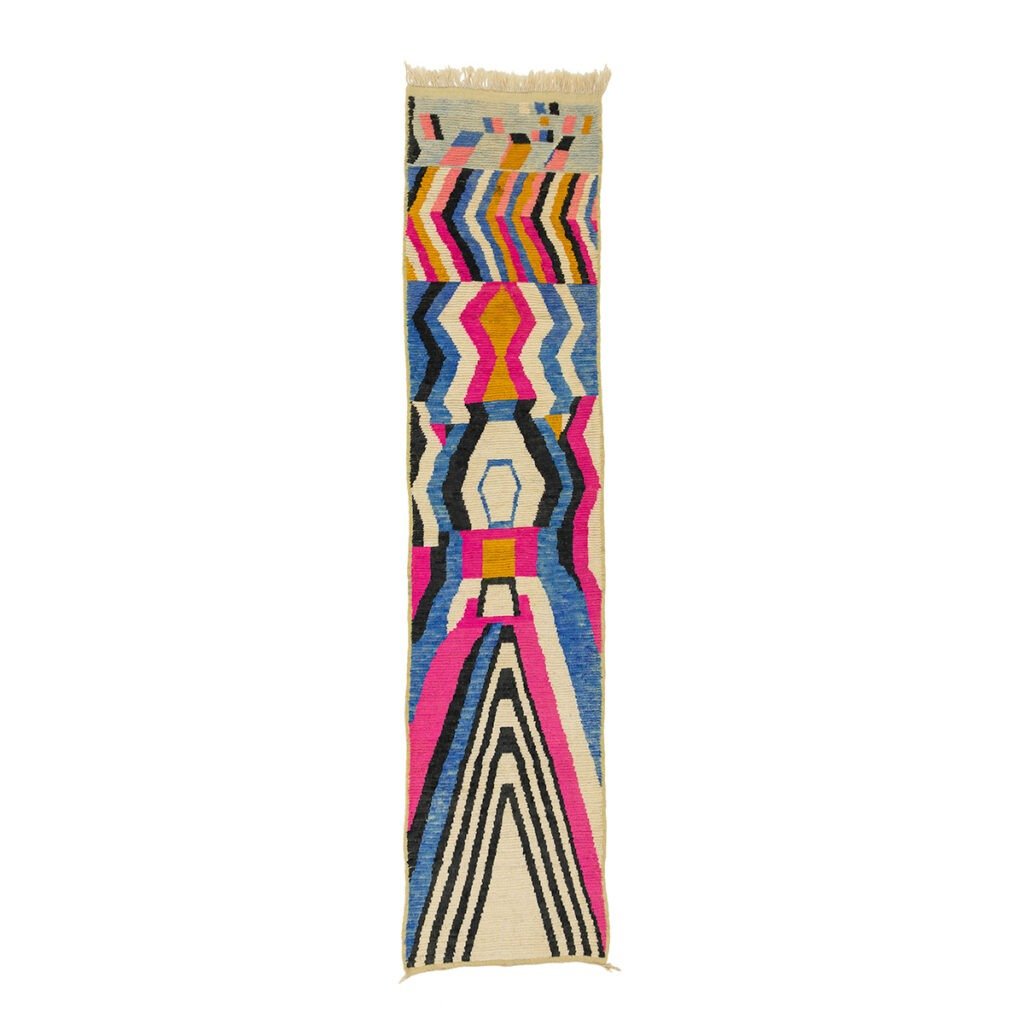 A vibrant runner rug featuring geometric patterns in shades of pink, blue, yellow, black, and white.