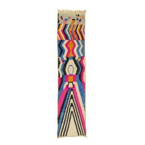 A vibrant runner rug featuring geometric patterns in shades of pink, blue, yellow, black, and white.