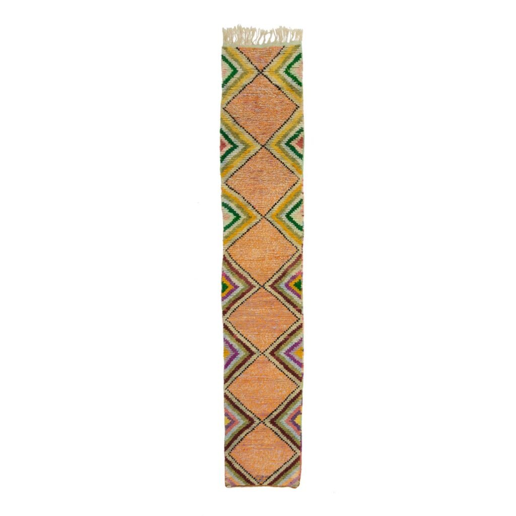 A vibrant woven runner with geometric diamond patterns in orange, green, yellow, and pink, accented by fringed edges.