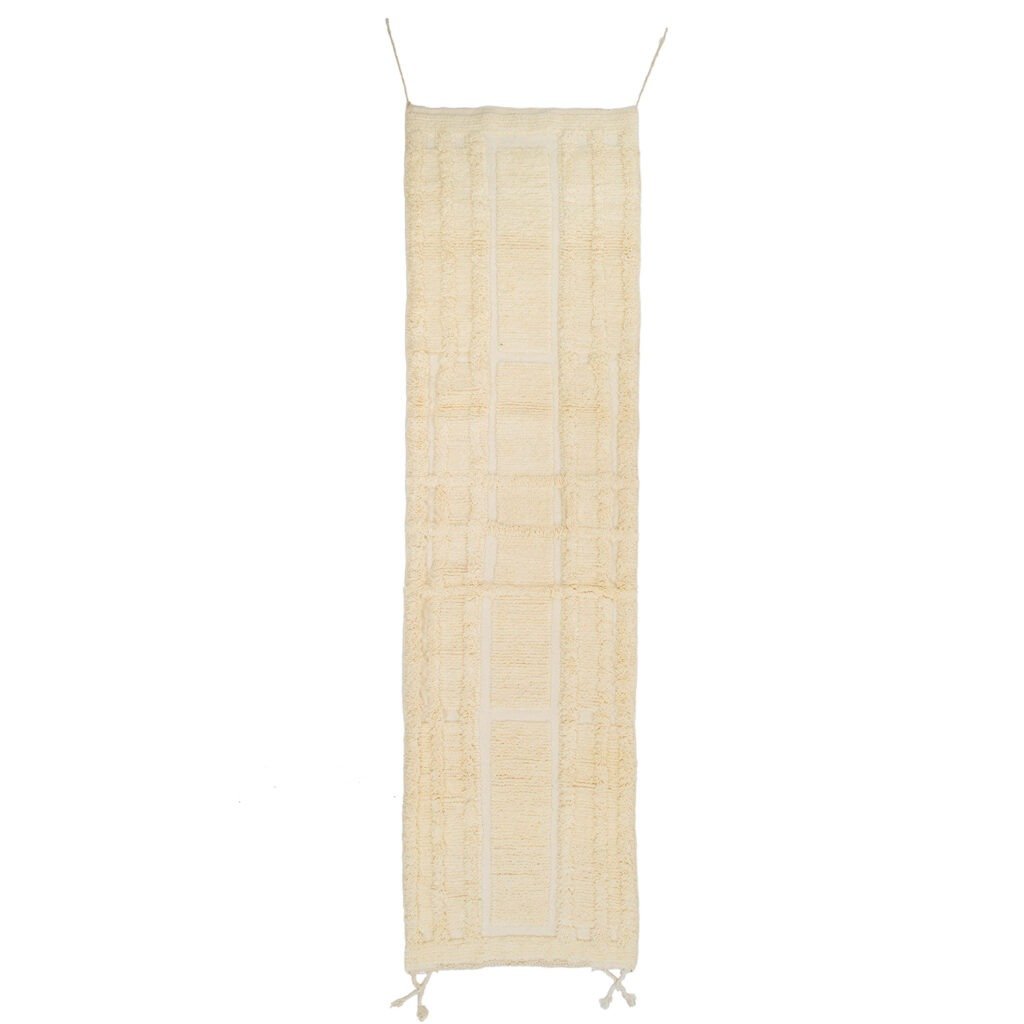 A cream-colored, rectangular, textured hanging wall piece reminiscent of a runner rug, featuring two loops at the top corners and elegant tassels at the bottom.
