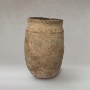 A rustic, beige ceramic pot with a rounded shape and a textured band near the rim is elegantly displayed on a neutral backdrop, exuding timeless charm.