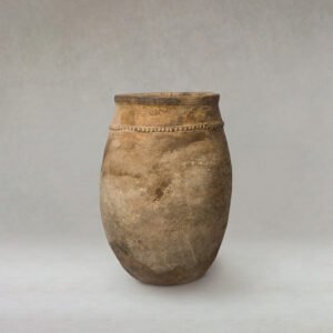A beautifully aged clay jar with a round bottom and intricate decorative ridge near the top sits gracefully against a neutral background, capturing the essence of ancient craftsmanship.