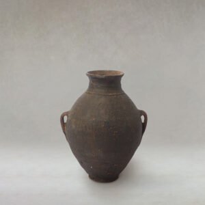 A vintage clay amphora with two handles stands prominently against a neutral background, its surface telling stories of age and wear.