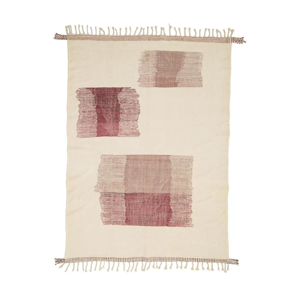 This handwoven rug in beige boasts fringe edges and showcases three abstract red and pink geometric patterns.