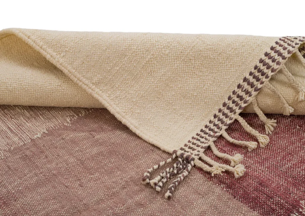 A handwoven textured beige and maroon rug with fringed ends and braided tassels.