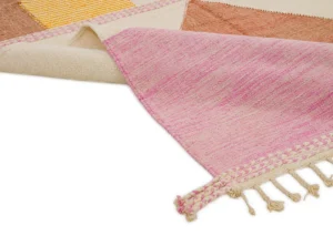 A close-up of a vibrant woven rug showcases pink, beige, and brown sections, with textured braided tassels adorning one edge. Perfect for adding a touch of warmth and color to your space.
