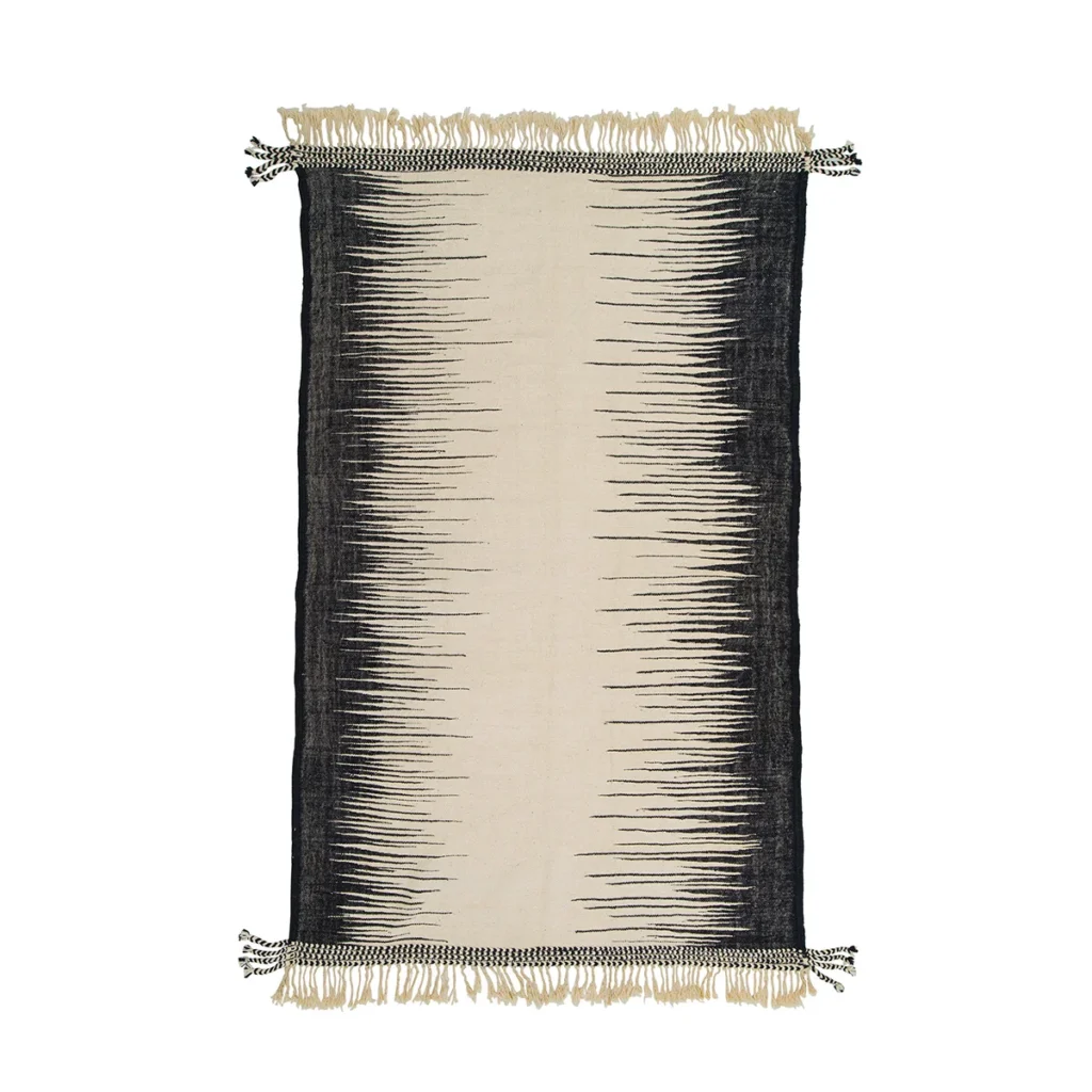 A flatweave rug with a central ivory band flanked by black, jagged edges, resembling sound waves. The rug is adorned with fringes on the shorter sides.