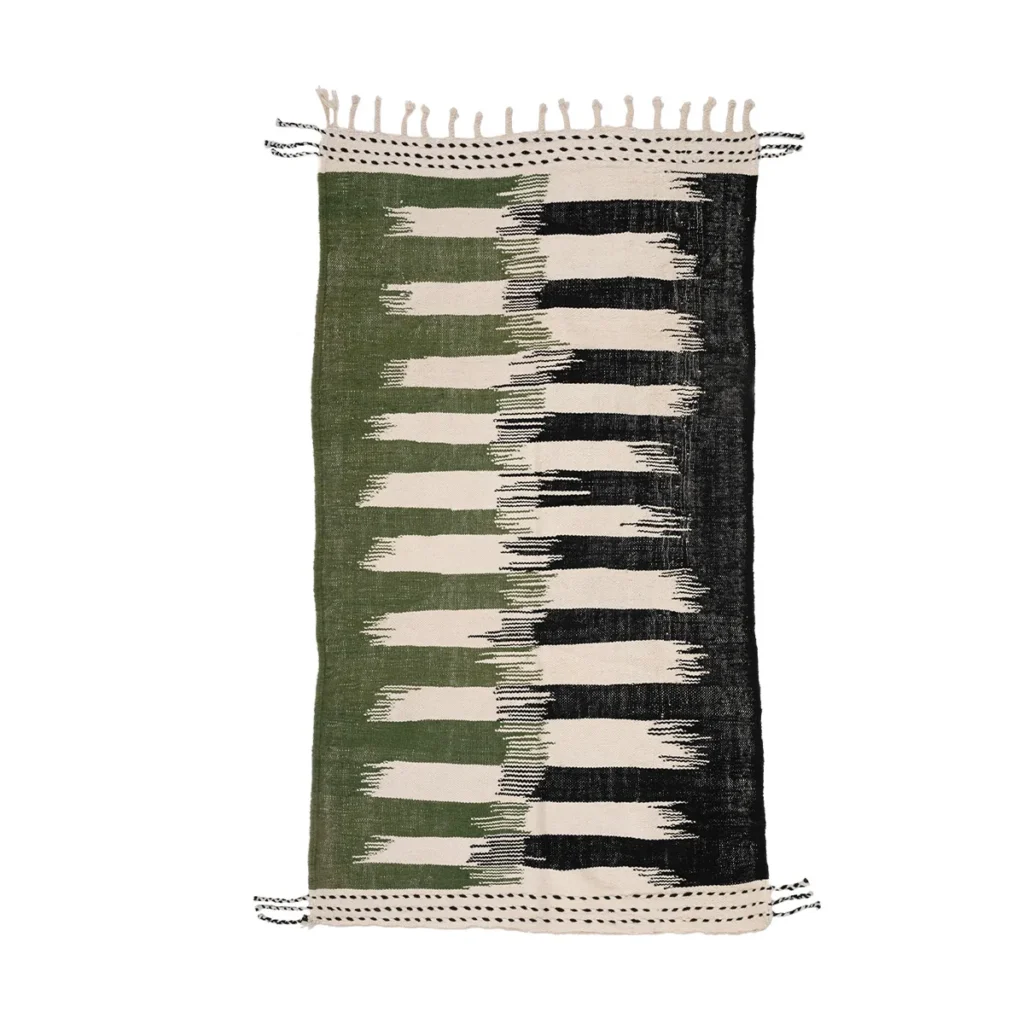 This rectangular Moroccan rug features a fringe and a green, black, and cream abstract pattern of alternating vertical strokes. A perfect flatweave rug to add elegance to any room.