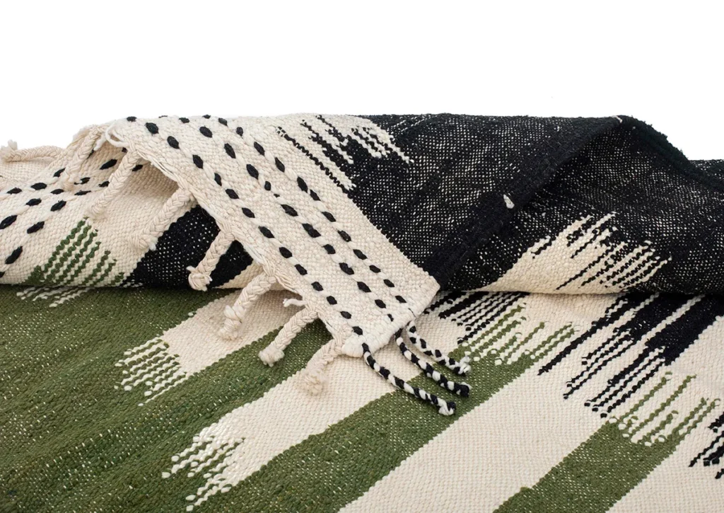 A vibrant flatweave rug showcasing green, black, and white stripes, accented by black dotted patterns and finished with fringed edges.