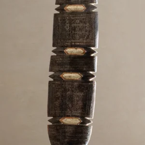 Close-up of a textured, dark brown wooden structure with intricate, hand-carved details and flat, diamond-shaped inserts arranged vertically, reminiscent of vintage wooden tent pegs.