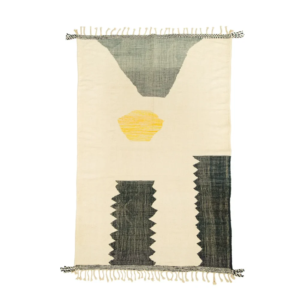 A handwoven rectangular rug with abstract geometric patterns in gray, white, and yellow, showcasing zigzag edges and fringe on two sides.