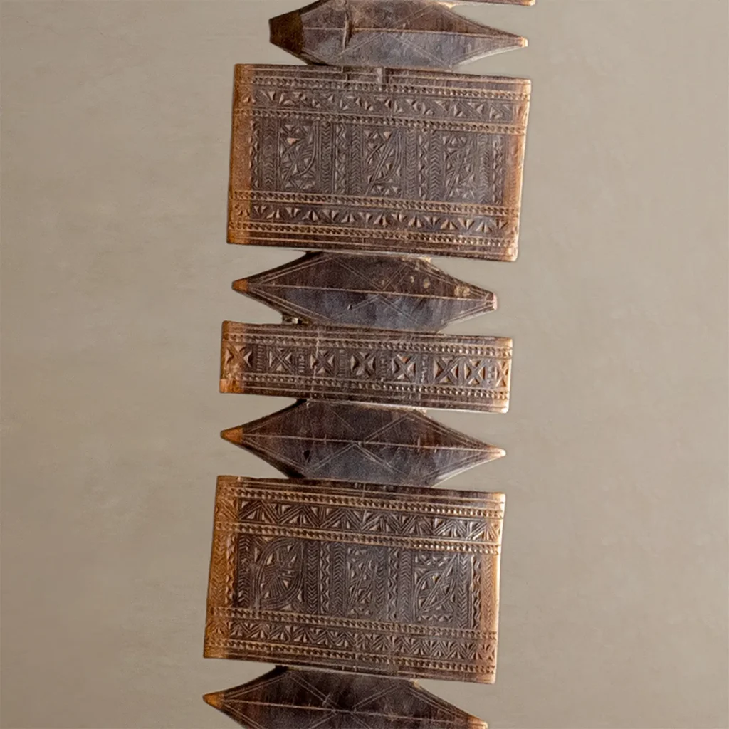 Rectangular and diamond-shaped, these hand-carved vintage ornaments boast intricate patterns connected in a vertical arrangement. The wooden tent peg design features rich brown tones and detailed engravings that evoke timeless elegance.