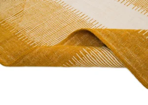 A close-up of a woven rugs corner reveals a beautiful yellow and white pattern, with the edge playfully turned up.