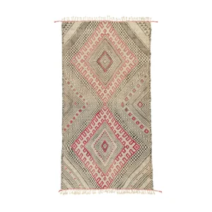 This vintage handwoven rug features a geometric pattern with diamond shapes in beige, red, and black tones. The edges are adorned with fringe detailing, adding a touch of sophistication.