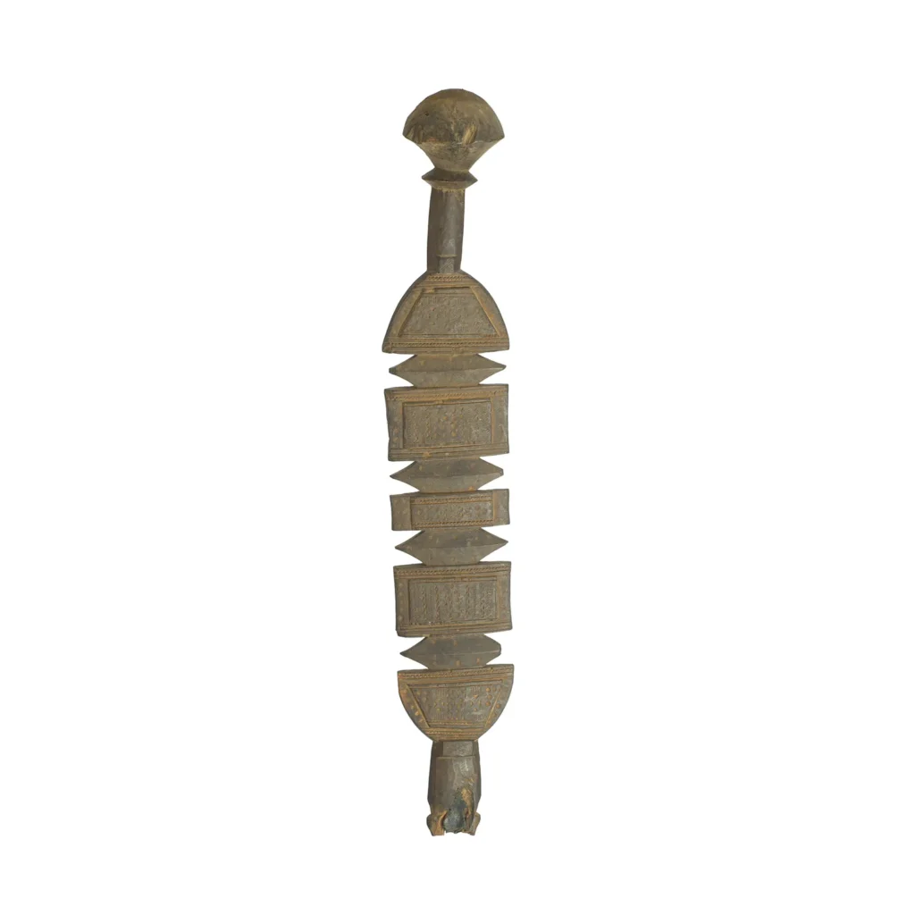 A hand-carved vintage wooden object with a spherical top, geometric orbs, and vertically arranged bands features detailed patterns and a small animal-like figure at the base, reminiscent of an elaborate tent peg from bygone eras.