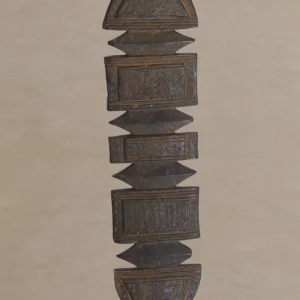 An elongated, vertical wooden sculpture with alternating square and triangular segments, featuring intricate hand-carved details reminiscent of vintage tent pegs, set against a neutral background.