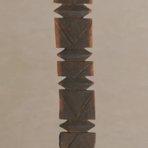 A vintage wooden carving, reminiscent of rustic tent pegs, showcases intricate geometric patterns and designs in rich brown and black tones, elegantly displayed against a plain backdrop.