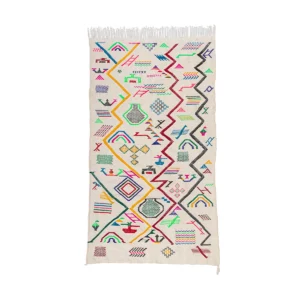 Handwoven geometric patterned rug with frayed edges on a white background.