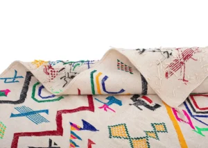 Close-up of a handwoven rug showcasing vibrant geometric and animal shapes, partially folded over.