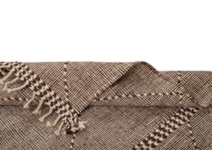 A woven brown and white textile with fringed edges, artfully folded at one corner against a crisp white background.