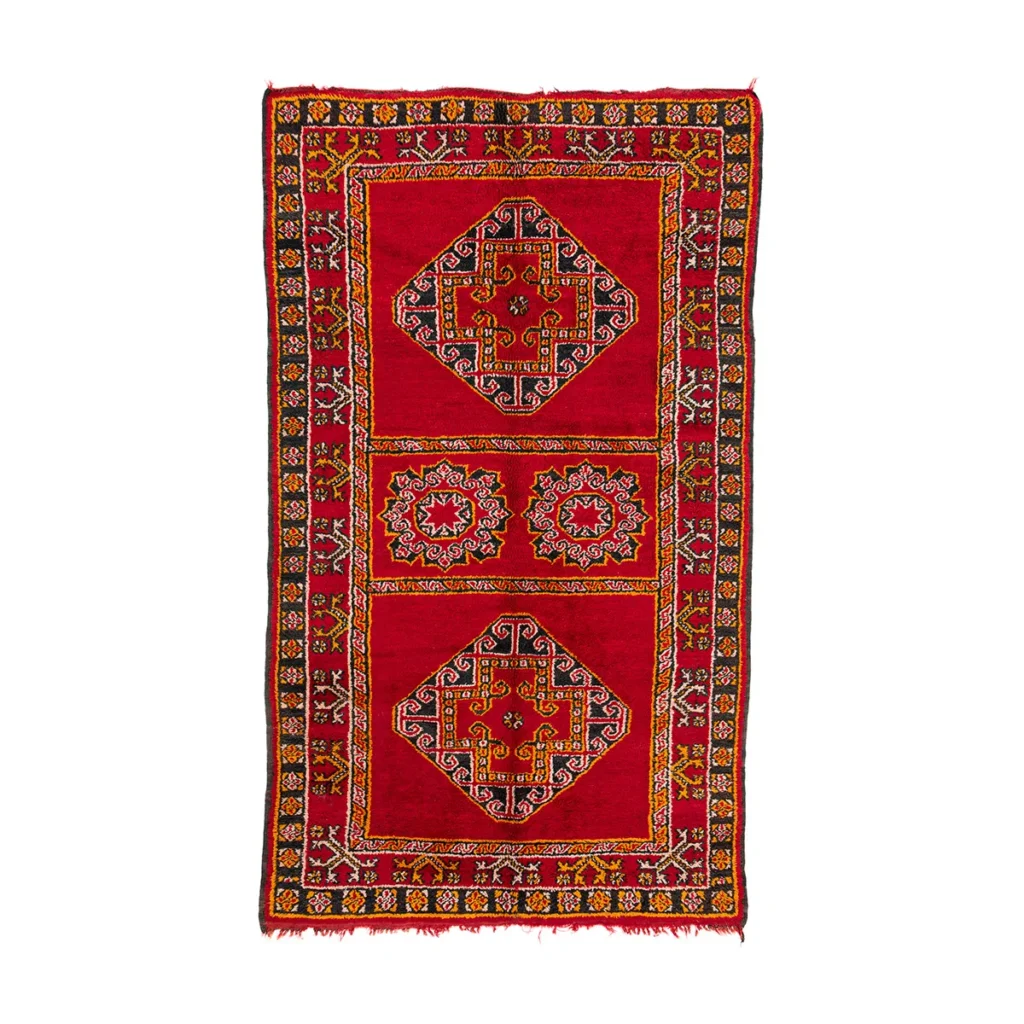 A rectangular red rug featuring intricate geometric patterns is accented with black, green, and yellow on a white background. This elegant design adds a vibrant touch to any living space.