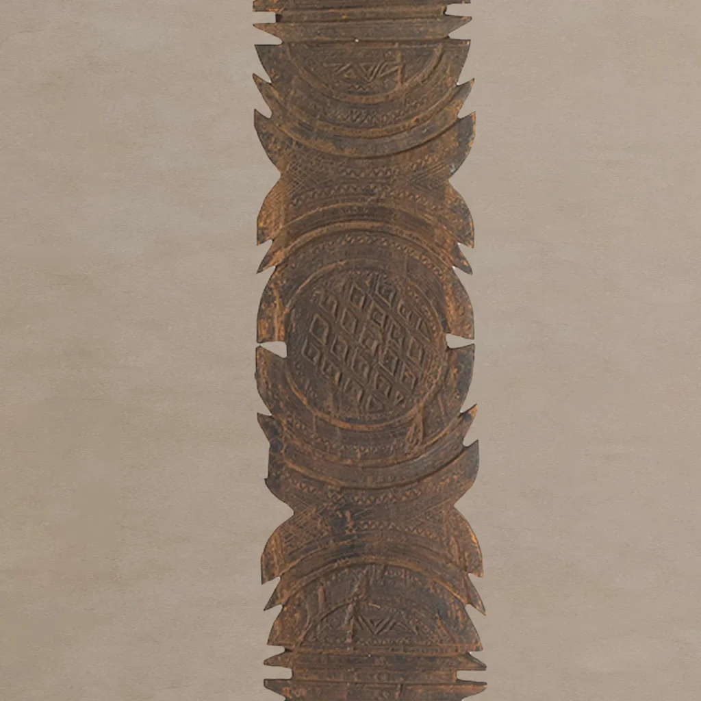 Hand-carved wooden sculpture with intricate geometric patterns, featuring repeating circular and diamond shapes, reminiscent of a vintage tent peg design, set against a plain background.