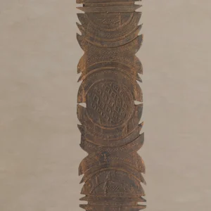 Hand-carved wooden sculpture with intricate geometric patterns, featuring repeating circular and diamond shapes, reminiscent of a vintage tent peg design, set against a plain background.