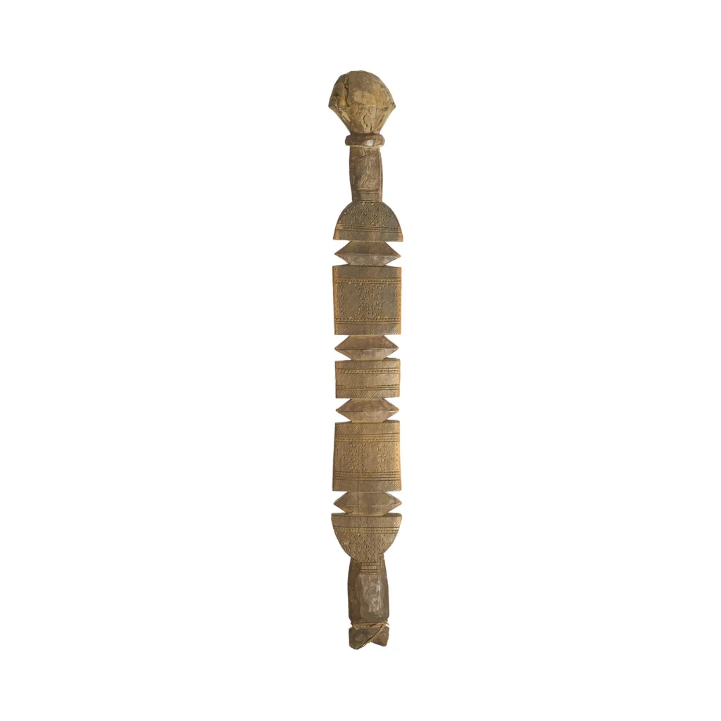 Hand-carved wooden ceremonial staff with intricate carvings and geometric patterns, reminiscent of a vintage tent peg, topped with a human-like figure.