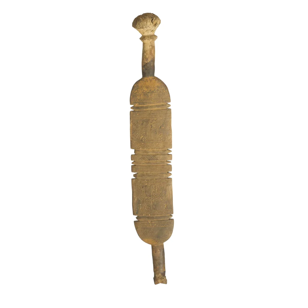 A vintage wooden ceremonial staff, hand-carved with intricate designs, boasts a rounded top and multiple engraved sections along its length, reminiscent of an ornate tent peg.